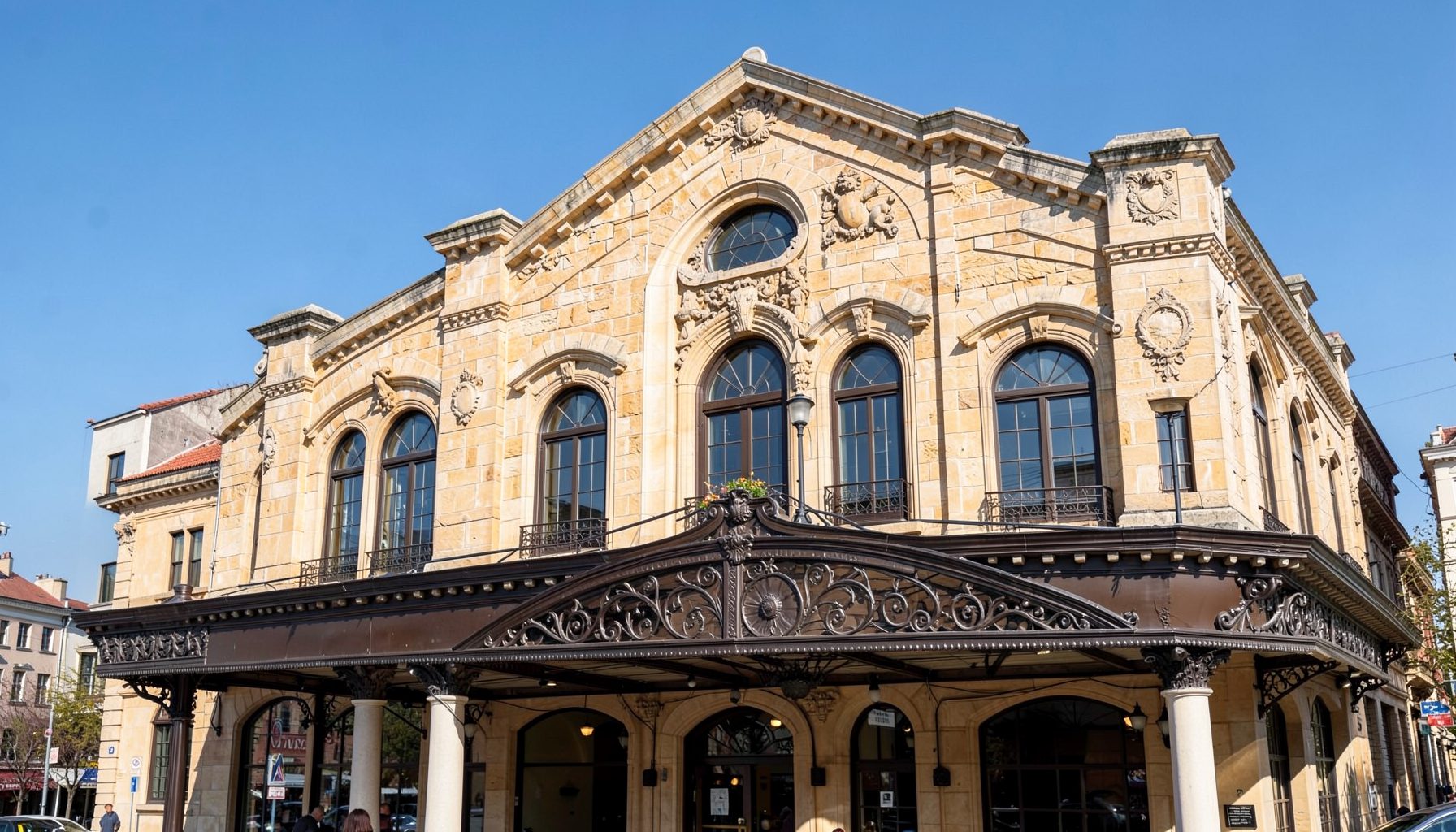 Elegant traditional theatre facade with arched windows and a marquee, warm stone tones under a clear blue sky